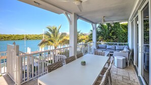 A covered outdoor area with a dining table and chairs, a sofa, and a ceiling fan. - Stunning **BRIGHT** Direct Waterfront 5/4 Home! Private Pool, Hot Tub & Dock! (Marathon)