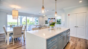 A modern kitchen with a large island, pendant lighting, and a view of the outdoors. - Stunning **BRIGHT** Direct Waterfront 5/4 Home! Private Pool, Hot Tub & Dock! (Marathon)