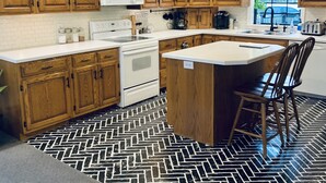 Una cucina con mobili in legno, un piano cottura bianco e un pavimento a spina di pesce.