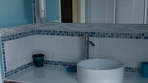 A bathroom with a white sink, blue-tiled backsplash, and a white cabinet above the sink. - Comfortable farm cottage 10 minutes from the sea (Bosville)