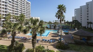 Un hotel con un amplio área de piscina, palmeras y vista al océano.