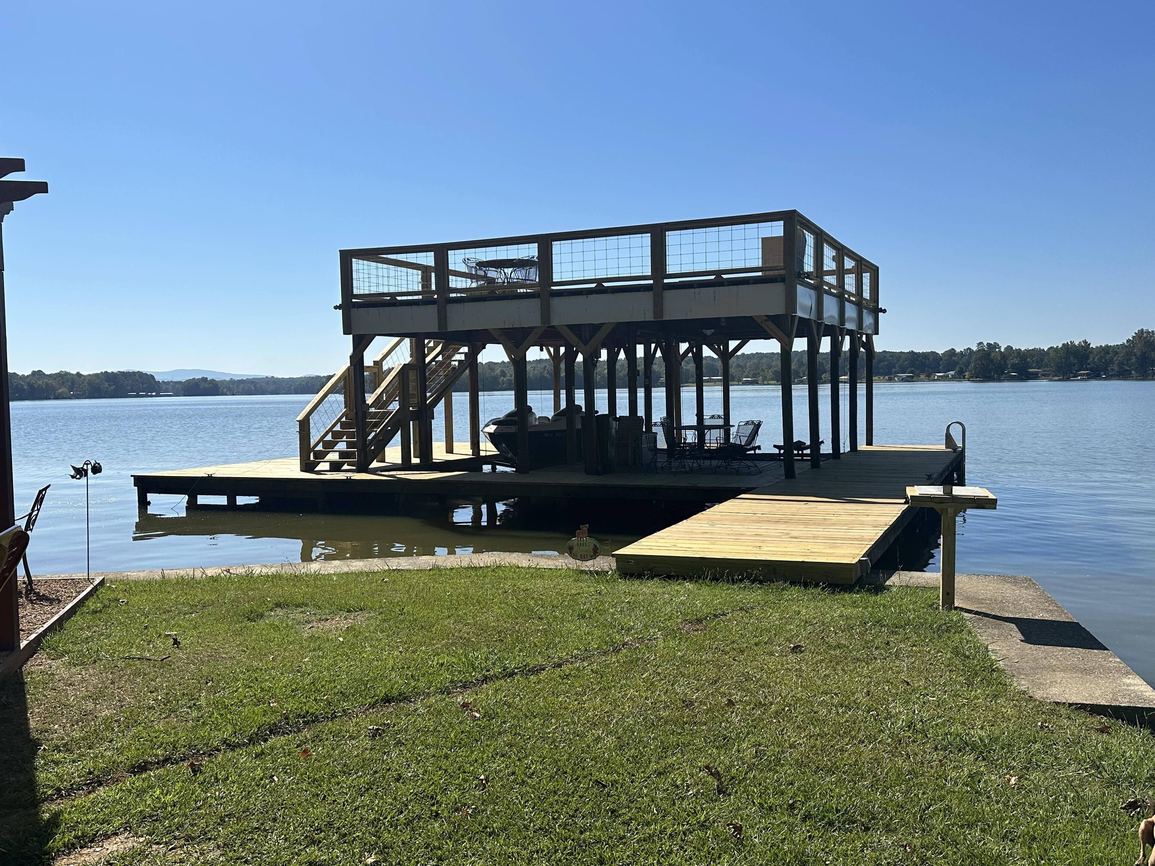 Un muelle de madera con una zona de estar cubierta y una escalera que lleva a una plataforma.
