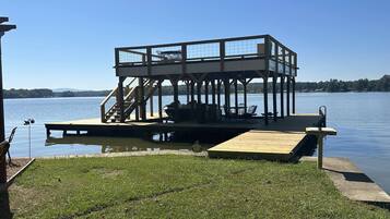 Un muelle de madera con una zona de estar cubierta y una escalera que lleva a una plataforma.
