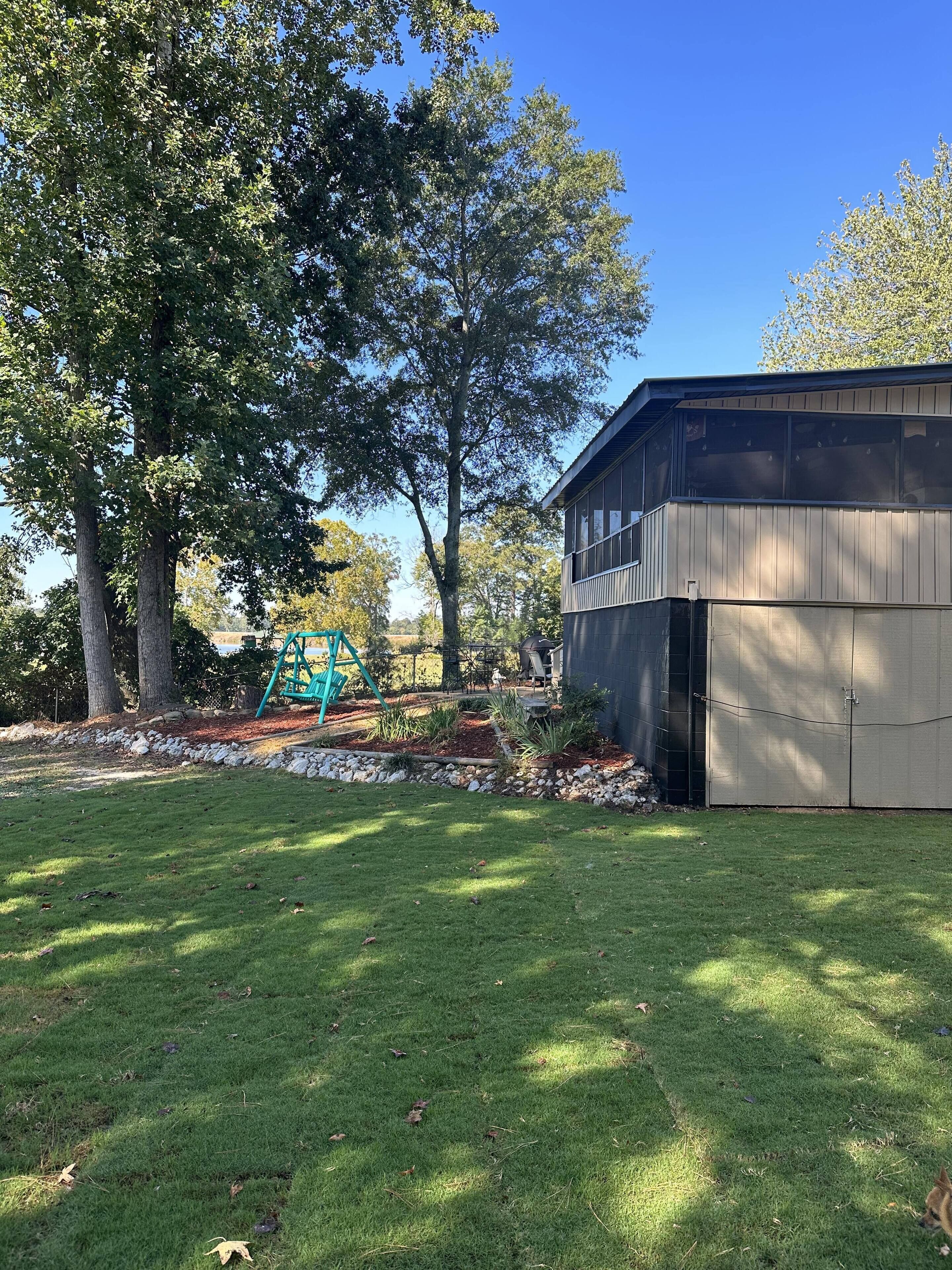 A backyard with a green lawn, a wooden shed, and a swing set.