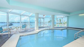 Una piscina interior con vistas claras al agua y un muelle al fondo.