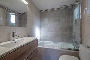 Et moderne badeværelse med et glasafskærmet brusebad, en hvid vask og et toilet.