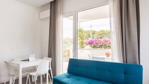 A modern room with a white dining table, four white chairs, a teal sofa, and a large window with curtains. - LM7 VILLA a stone's throw from the sea, Infinity Pool, Hydro, Wi-Fi, Garden (Fontane Bianche)