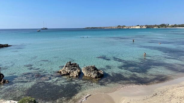 A beach with clear turquoise water, rocky formations, and a distant ship. - LM7 VILLA a stone's throw from the sea, Infinity Pool, Hydro, Wi-Fi, Garden (Fontane Bianche)