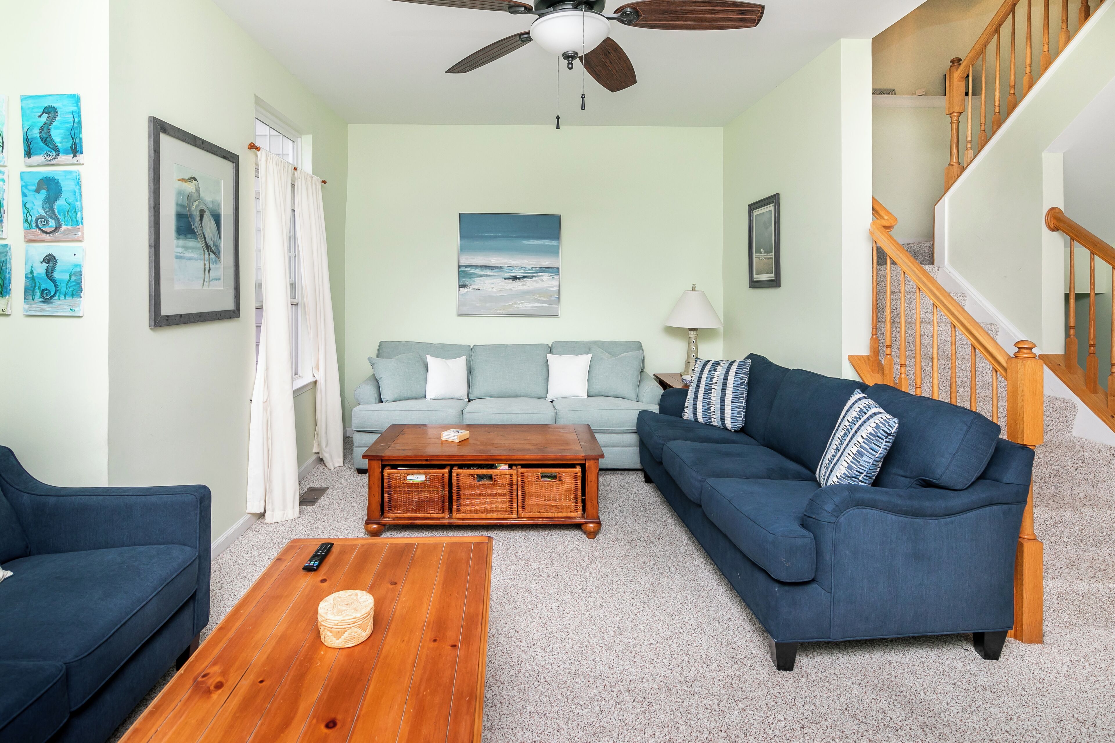 A living room with a blue sofa, a wooden coffee table, and a ceiling fan.