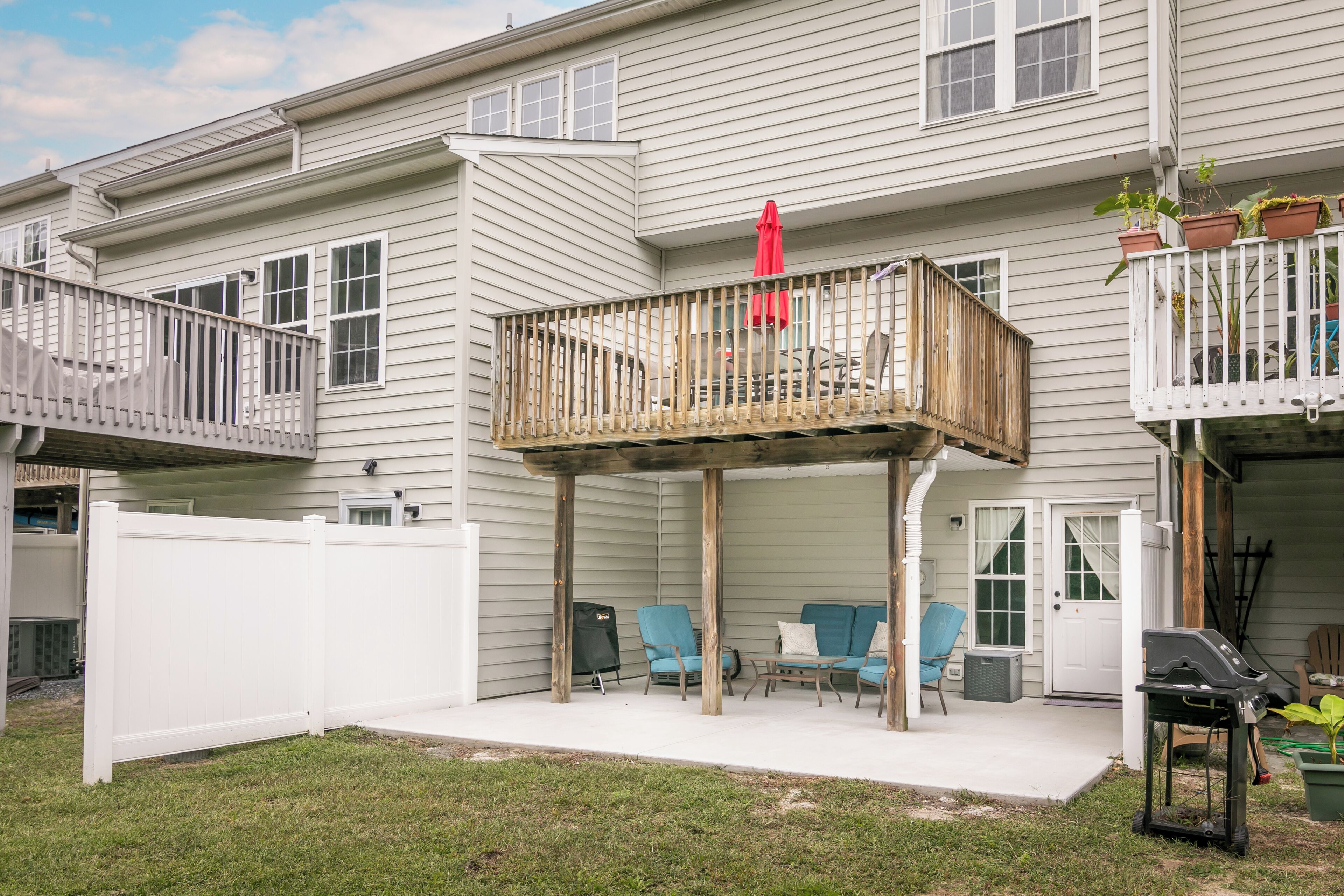 A two-story house with a covered patio area, outdoor seating, and a barbecue grill.