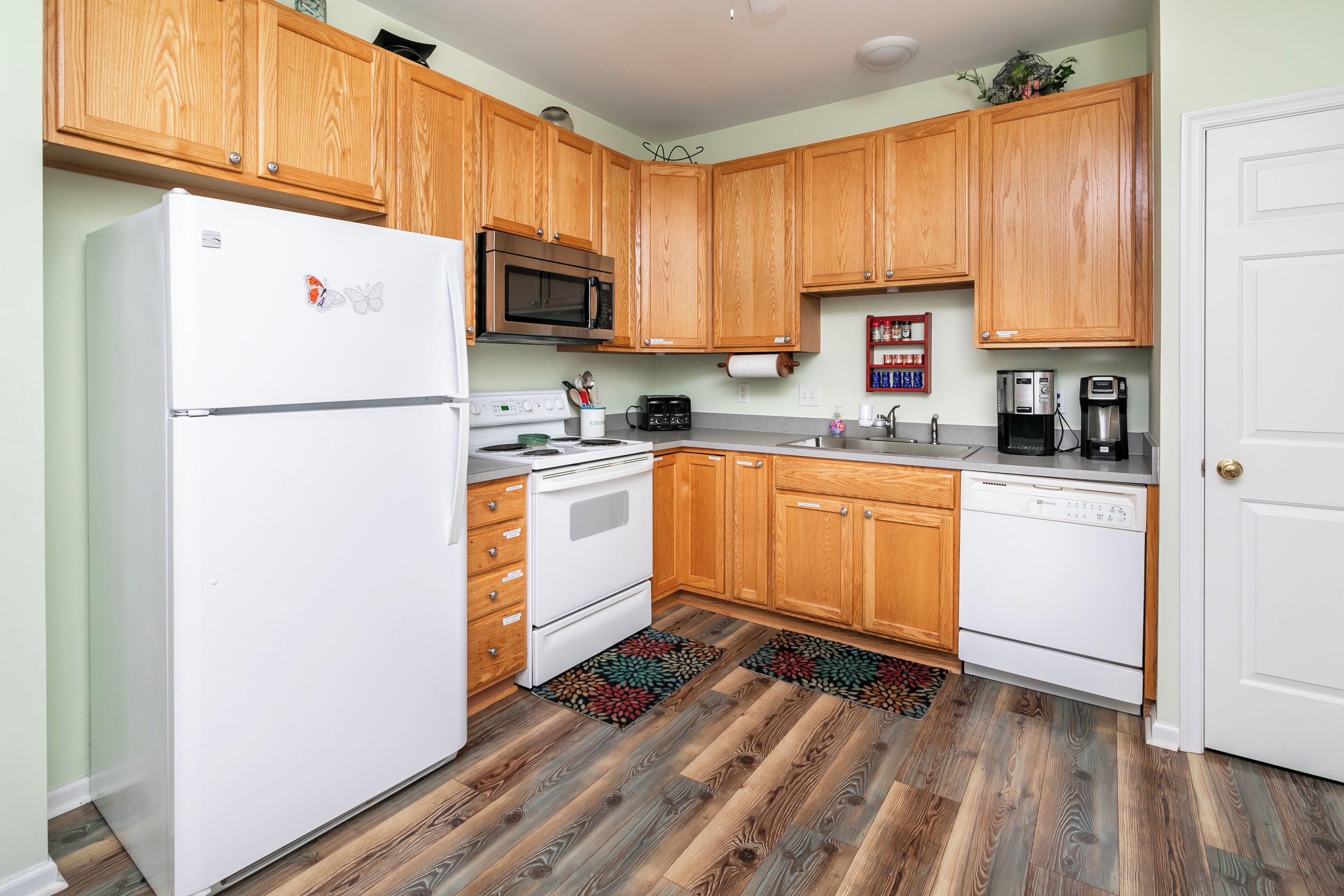 A kitchen with wooden cabinets, a white refrigerator, a microwave, a stove, and a dishwasher.