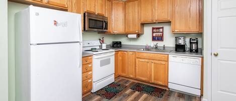 A kitchen with wooden cabinets, a white refrigerator, a microwave, a stove, and a dishwasher.