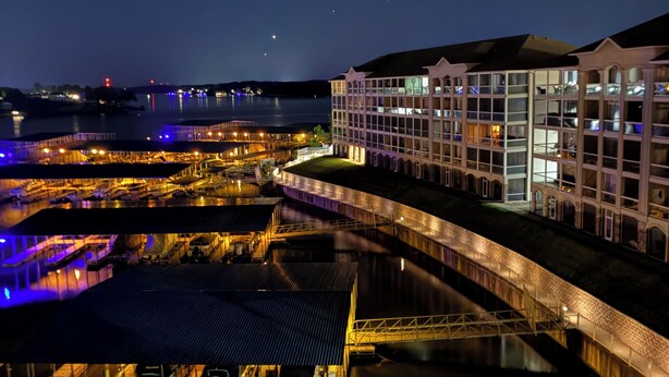 A waterfront hotel with a glass facade, a covered outdoor area, and a view of the water.