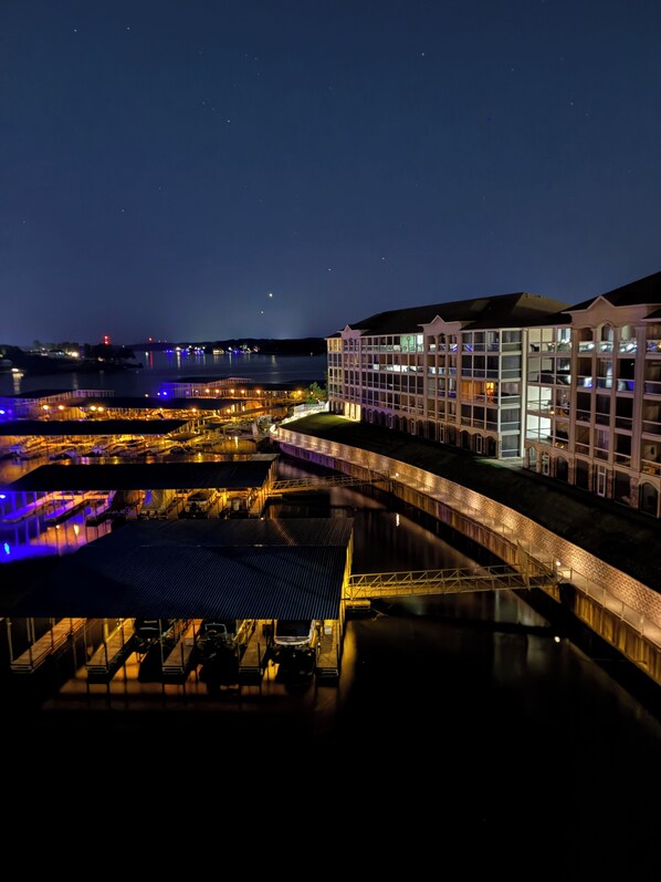A waterfront hotel with a glass facade, a covered outdoor area, and a view of the water.
