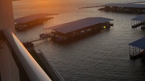 A sunset view from a balcony overlooking a marina with several docked boats and covered structures.