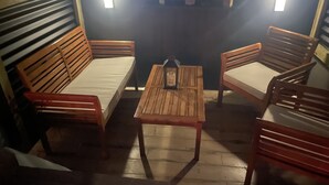 Un rincón acogedor con muebles de madera y una pequeña mesa, que incluye una lámpara en la pared.
