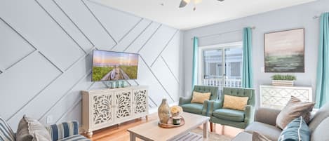 A modern living room with a sofa set, a coffee table, a TV, and a ceiling fan.