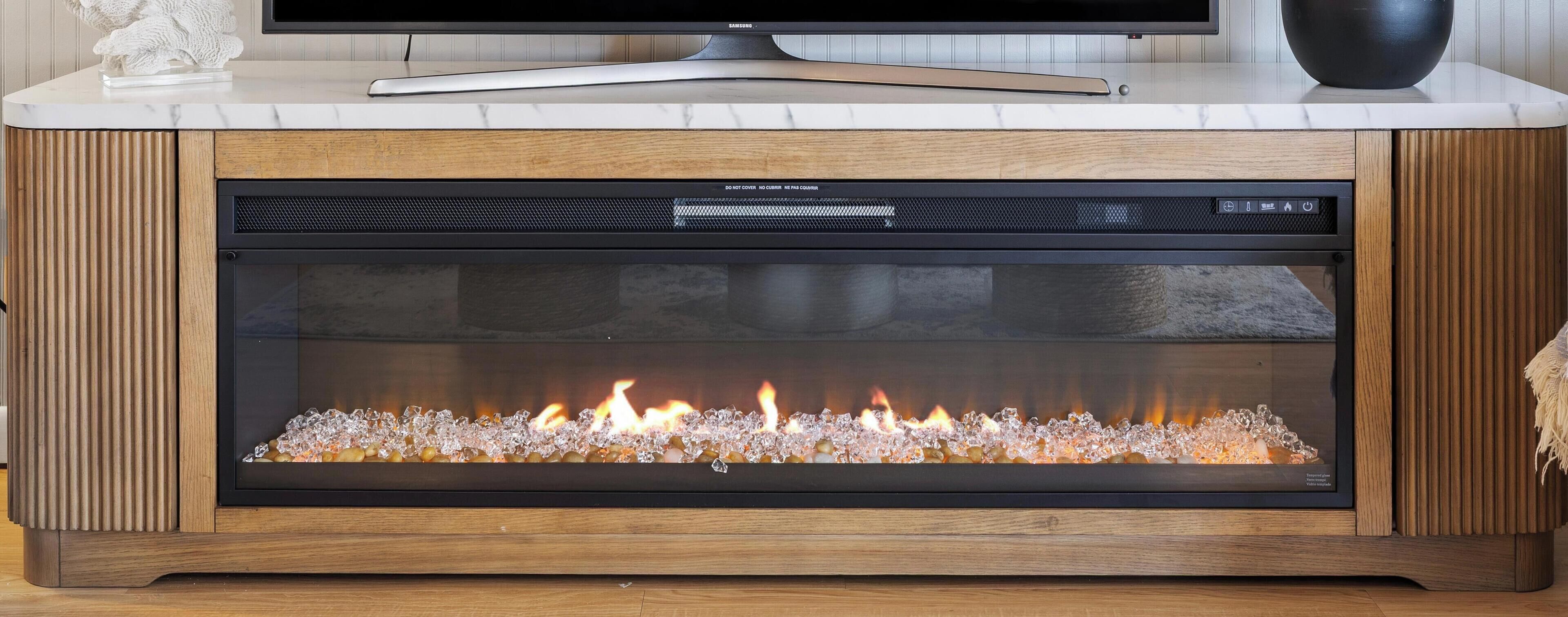 Una chimenea moderna con frente de vidrio, un panel de control y un gabinete de madera.