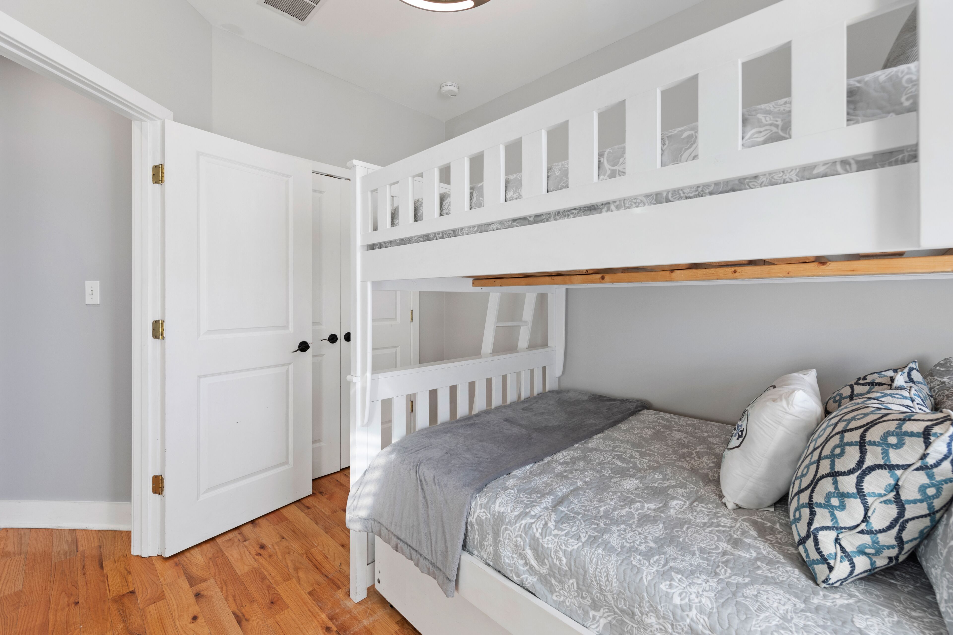 A bedroom with a bunk bed, a door, and a patterned bedspread.