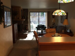 Cozy living room with a fireplace, dining area, and comfortable seating area offering a view of the outdoors.