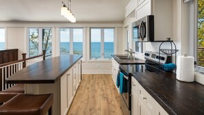 Una cocina con una isla grande, piso de madera y vista al mar.