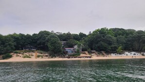 Propiedad frente al lago con playa, muelle de madera y una casa con amplia terraza.