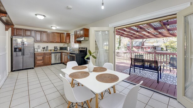 A kitchen with white cabinets, a stainless steel refrigerator, and a dining area with a white table and chairs. - Atlanta Luxury Home 1 mi from The Battery Sleeps 8 (Smyrna)