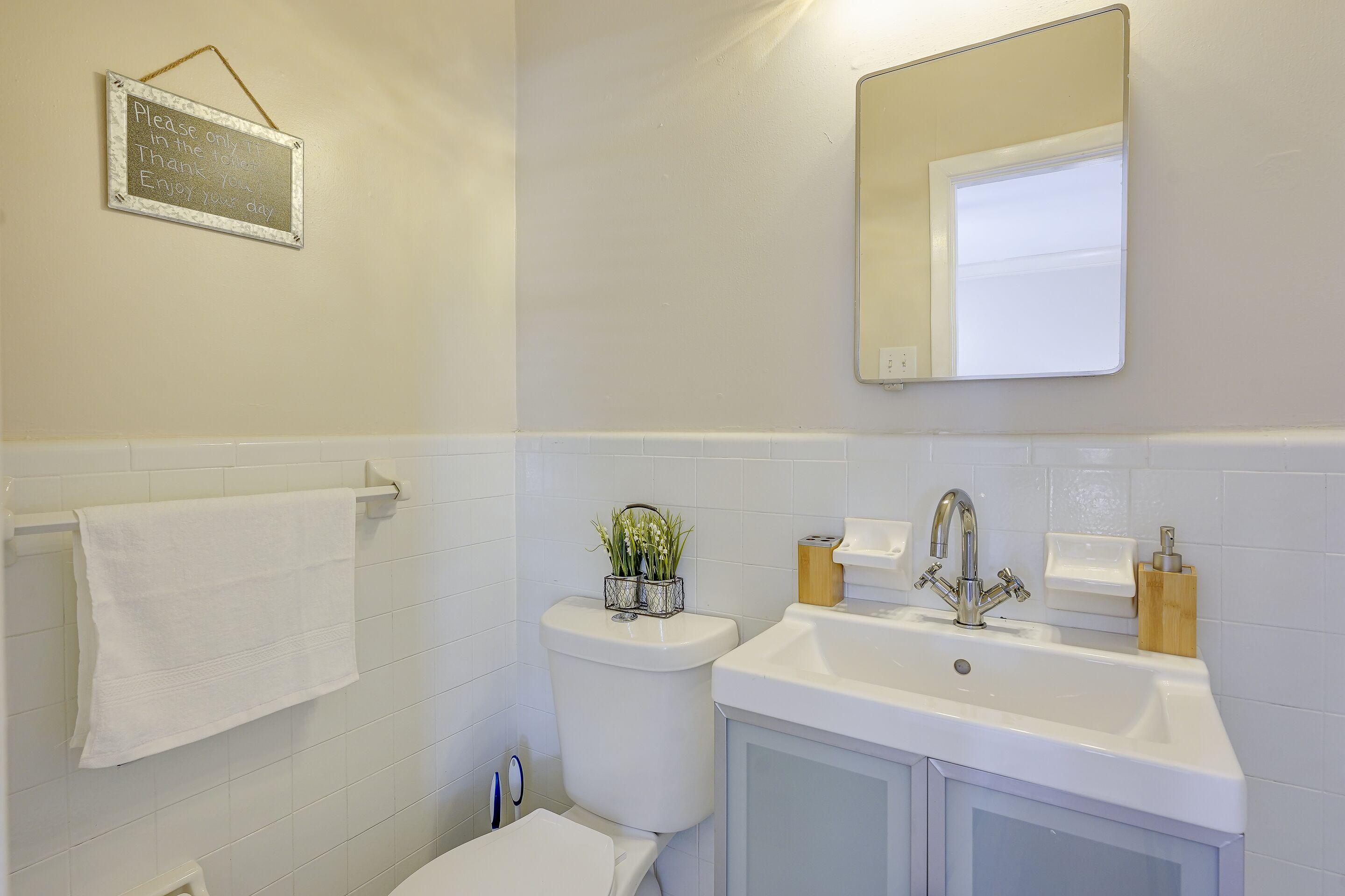 Een badkamer met toilet, wastafel en spiegel.