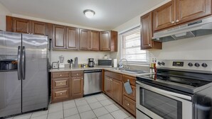 A modern kitchen with stainless steel appliances, wooden cabinets, and a tiled floor. - Atlanta Luxury Home 1 mi from The Battery Sleeps 8 (Smyrna)