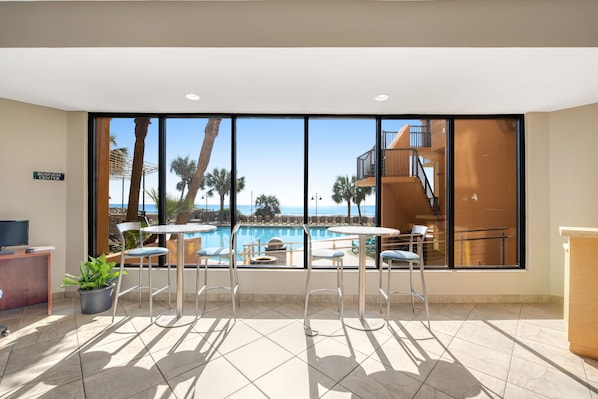 Enjoy a panoramic view of the pool area from the comfort of this stylish room, featuring a desk, seating area, and potted plant.