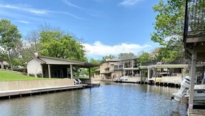A calm water body with a dock and boats, surrounded by residential buildings and greenery.
