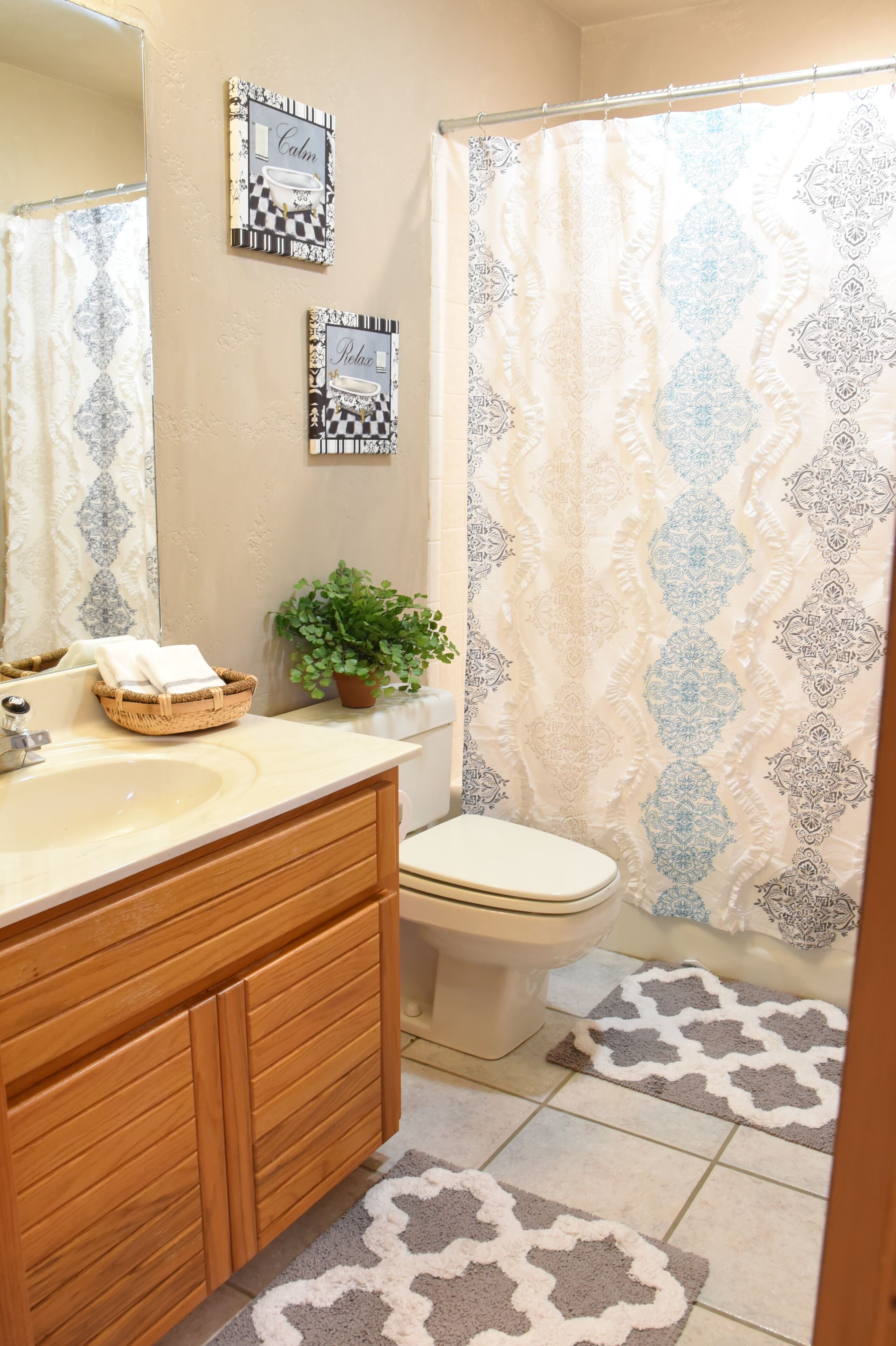 A bathroom with a wooden vanity, a sink, a toilet, and a shower curtain.