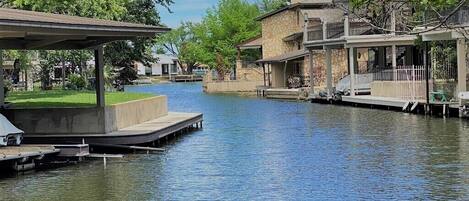 A canal with docked boats, a covered seating area, and buildings with stone facades.