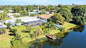 A residential area with a large greenhouse, a dock, and a calm lake.