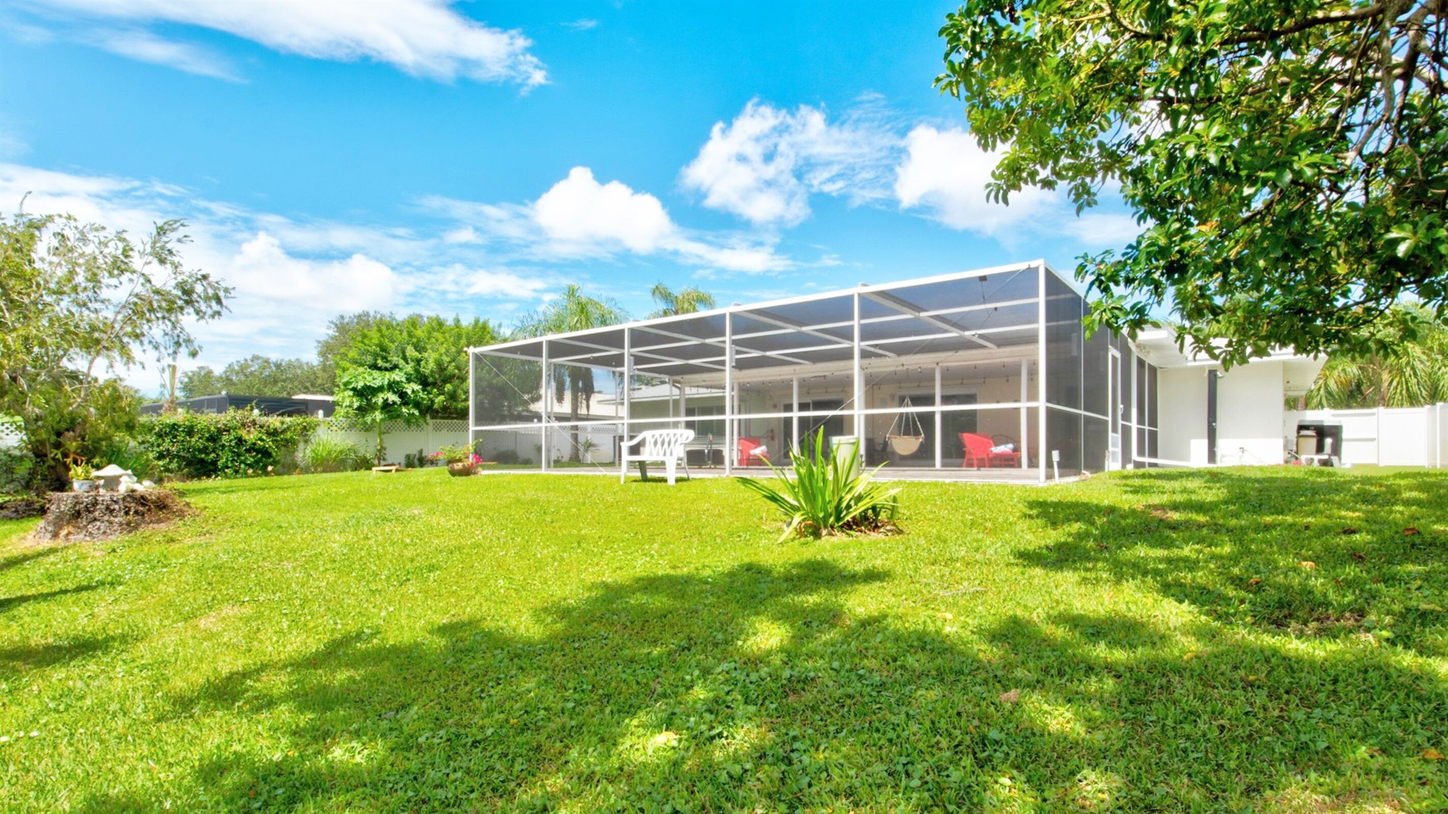 Een modern huis met een grote glazen gevel, omgeven door een verzorgd gazon en bomen.