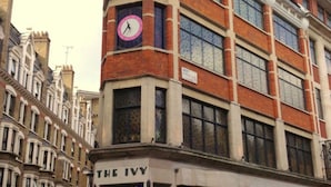 A building with a clock on the corner, a sign reading "THE IVY," and a street sign indicating "WEST STREET WZ2."