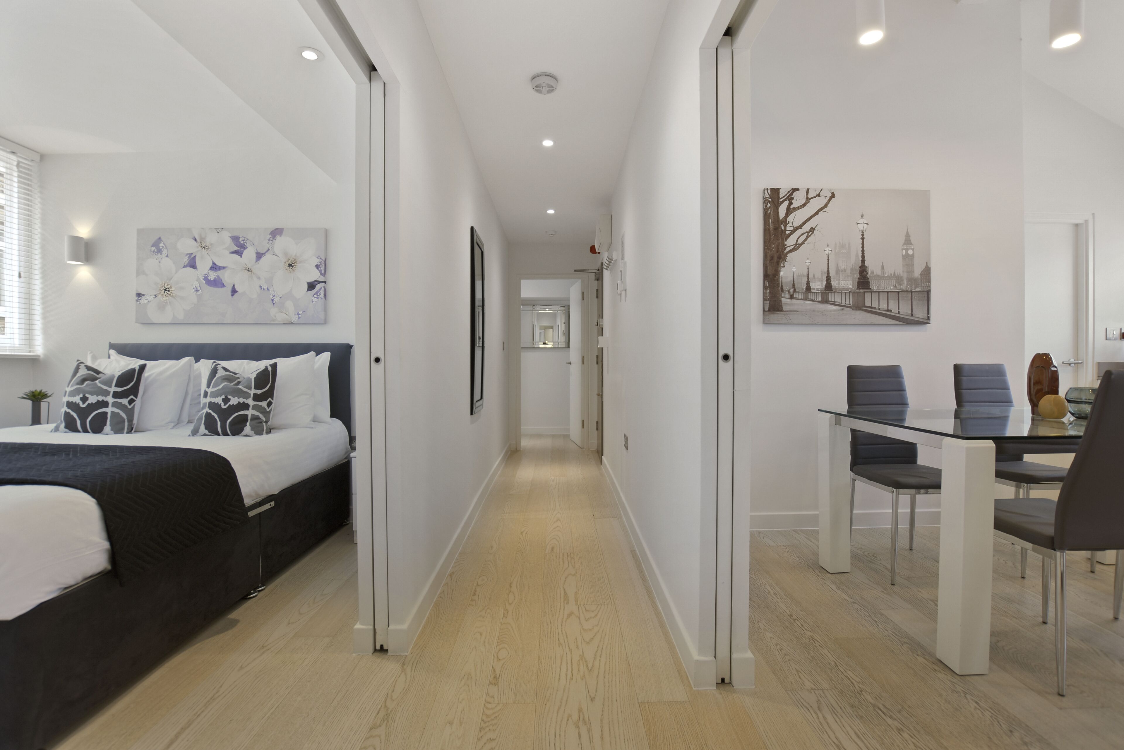 Ein modernes Hotelzimmer mit Bett, Essbereich und einem Flur, der zu einem weiteren Raum führt.