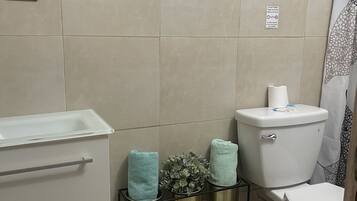 Un baño con inodoro, lavamanos y un cubo de basura.