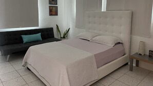 Una camera da letto con un letto, un divano, un comodino e una pianta in vaso.