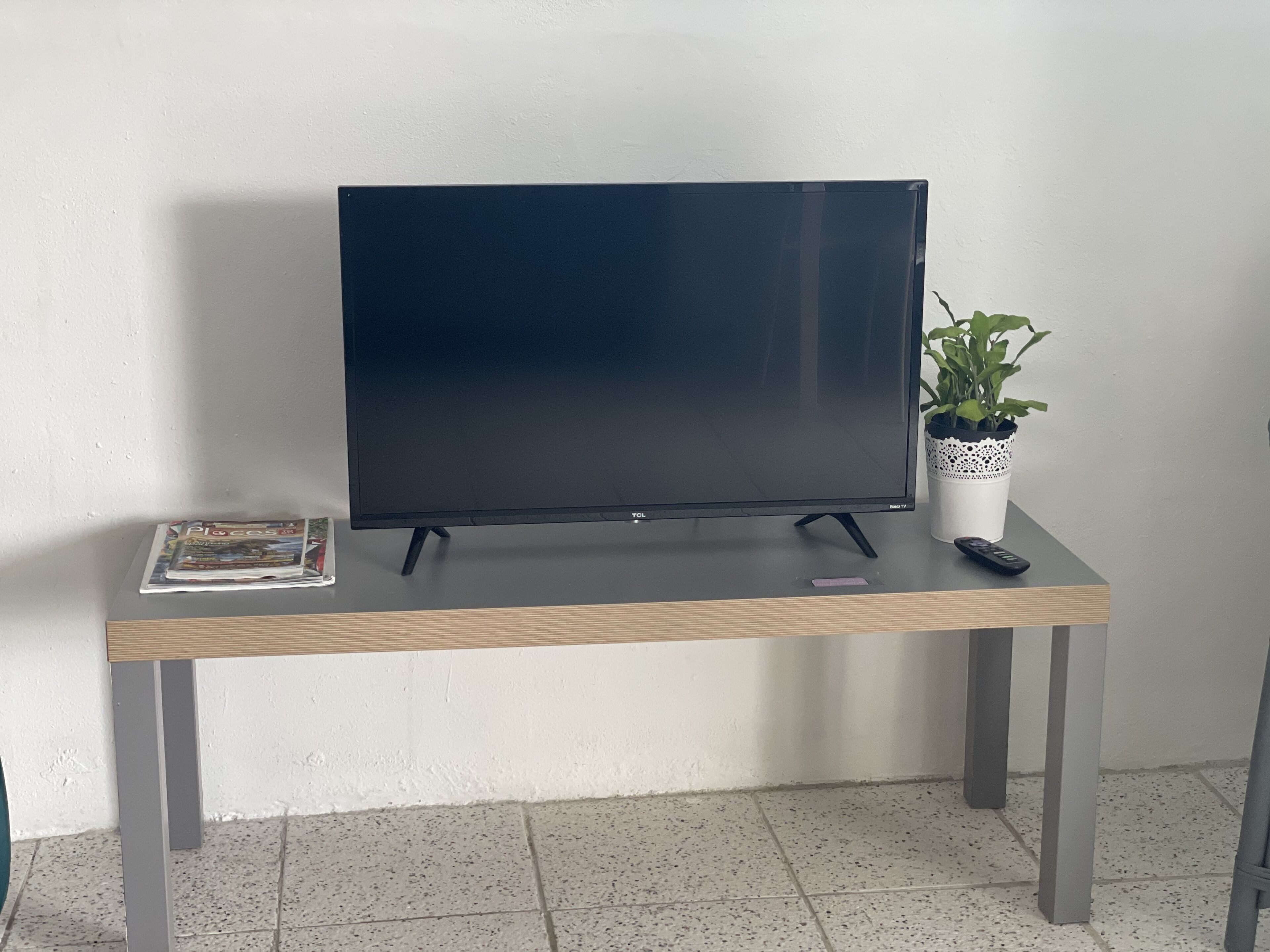 Ein Flachbildfernseher auf einem Holztisch mit Fernbedienung und einer Zeitschrift.