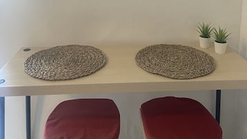 A room with two framed abstract artworks, a woven placemat, a small potted plant, and red cushioned seating.