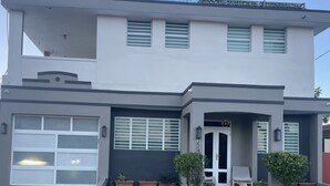 Una casa moderna a due piani con garage, un portico con gradini e piante in vaso.
