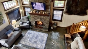 A spacious living room with a stone fireplace, a mounted deer head, and a large fur rug.