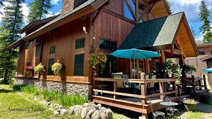 A lodge with a stone foundation, wooden exterior, and a porch with outdoor seating.