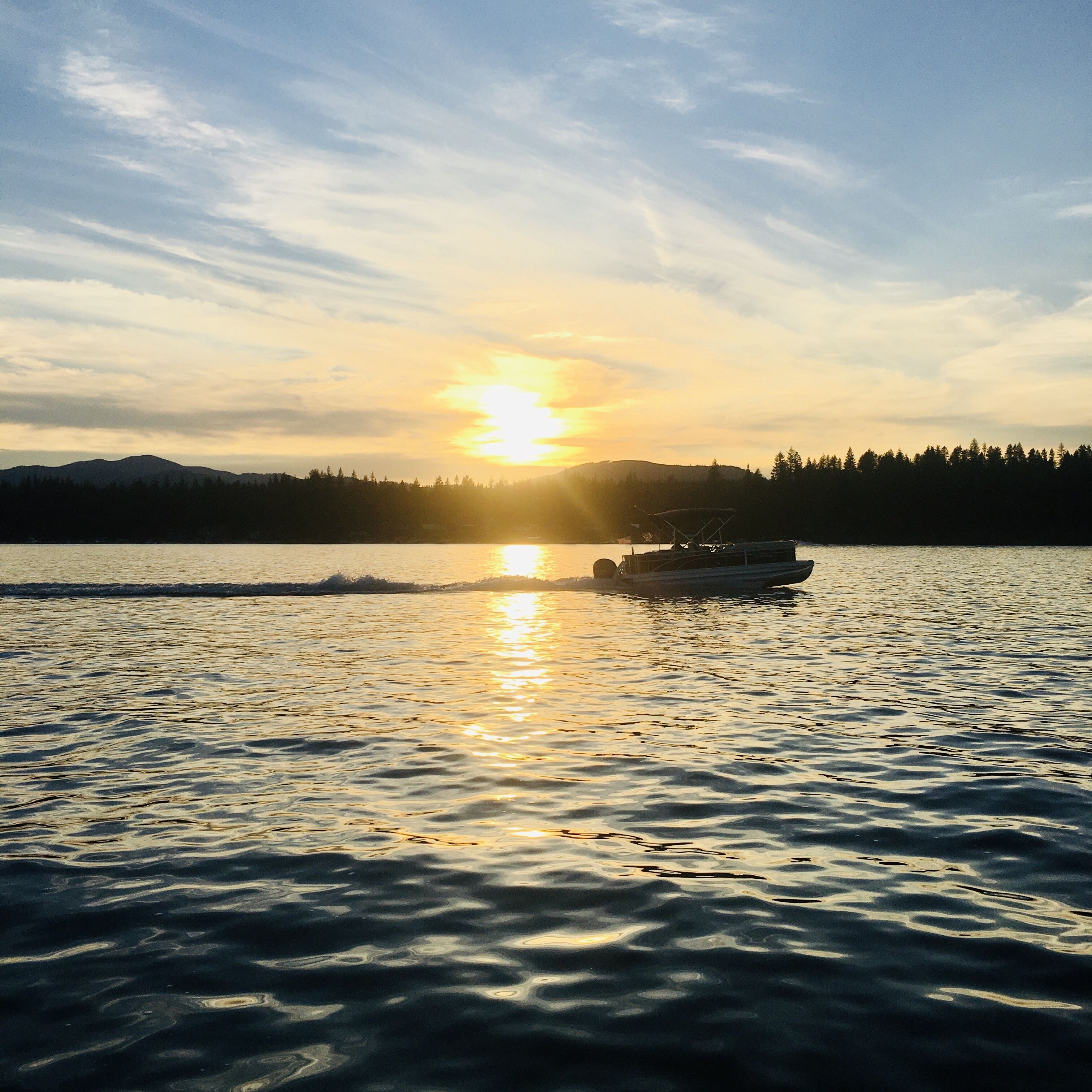 A boat on a calm lake with a sunset in the background.