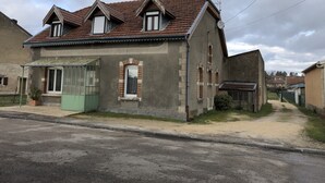 Una casa de dos pisos con techo de tejas, un pequeño porche y un plato parabólico visible.
