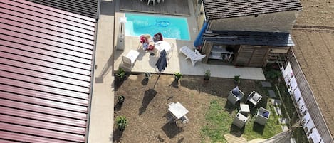A residential property with a swimming pool, outdoor seating, and a garden area.