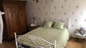 Un dormitorio con cama, armario de madera, mesita de noche, lámpara y un oso de peluche.