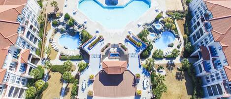 Un resort con varias piscinas, una piscina central con forma de corazón y vistas a la playa.