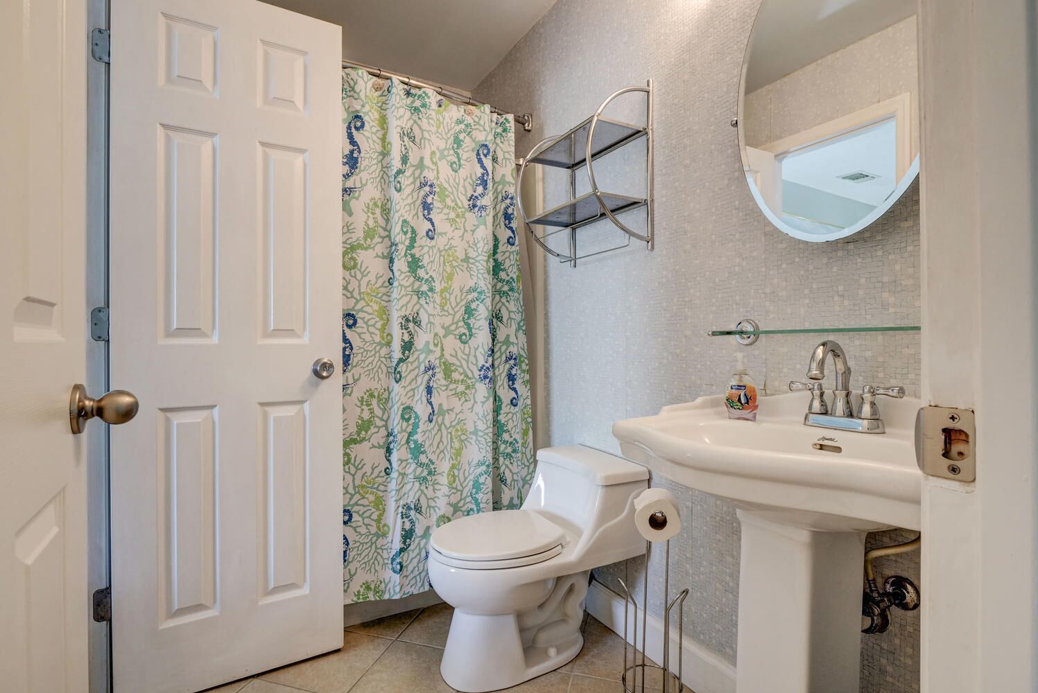 Une salle de bain équipée de toilettes, d’un lavabo, d’un rideau de douche et d’un miroir.